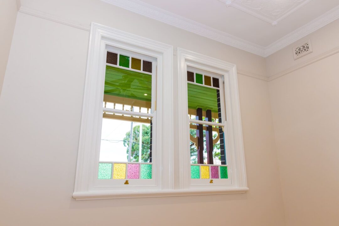 A room with white windows having colourful stained glass on them